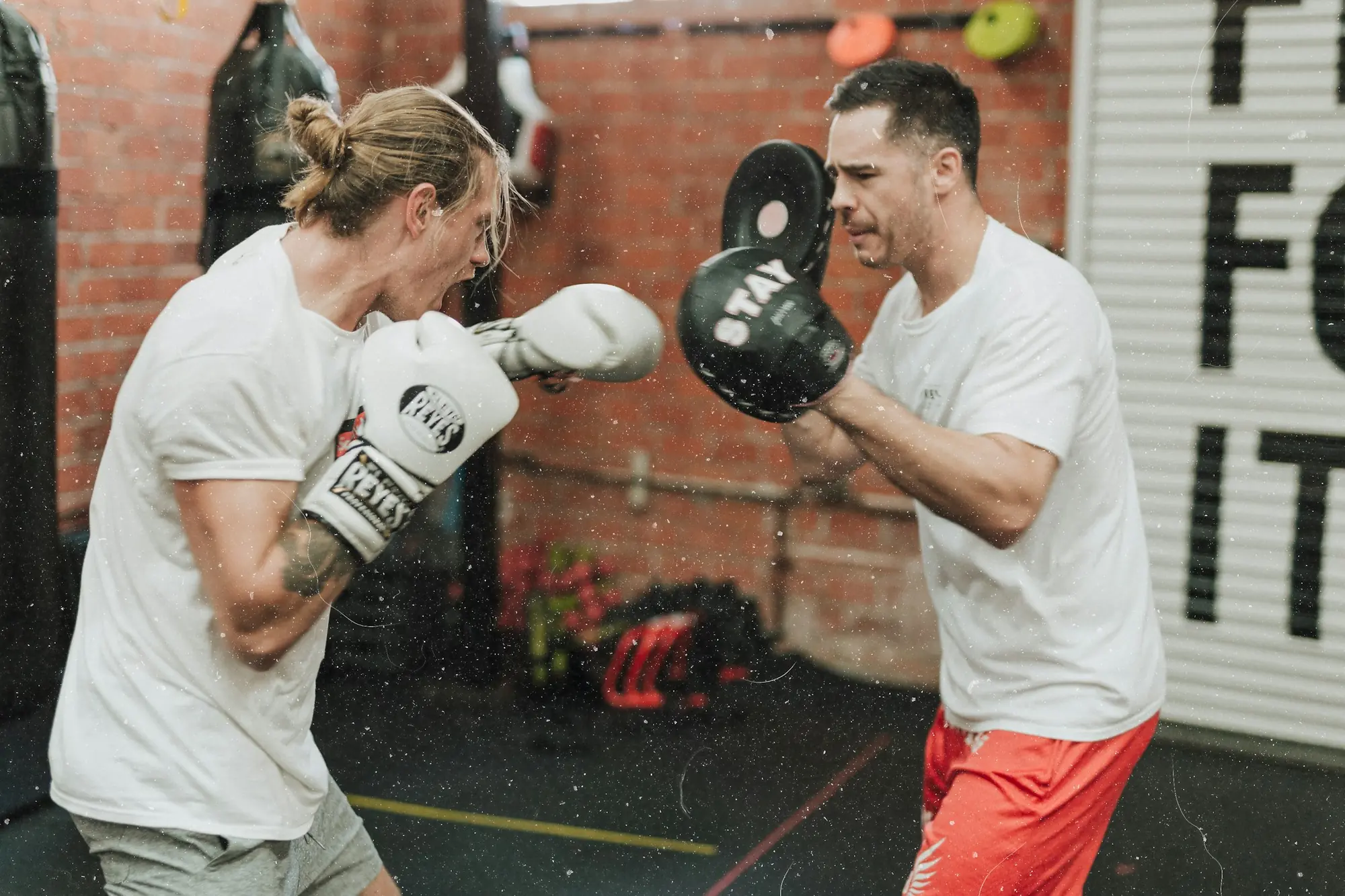 A boxer throwing a punch into a coach's focus mitt